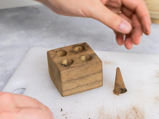 DIY incense cone mold wooden block with 4 conical cavities and finished cone shown on white surface