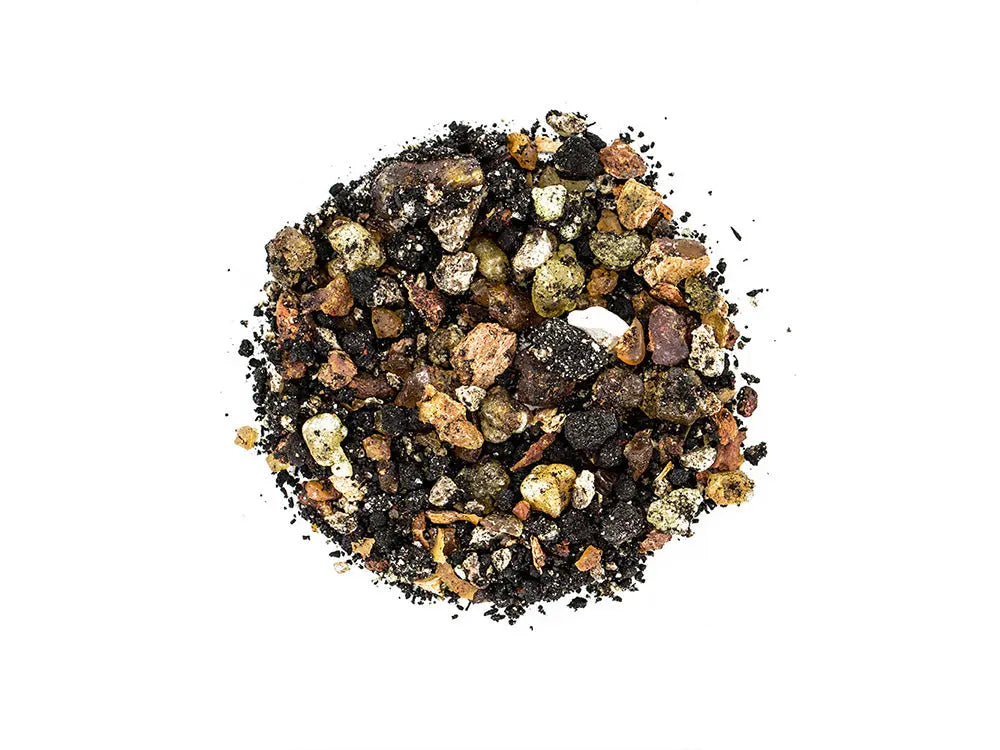 Pontifical incense blend of dark and golden resin granules in circular arrangement on white background