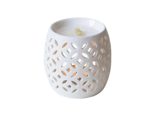 White porcelain firefly diffuser with floral cutout pattern, tea light candle glowing through decorative openings