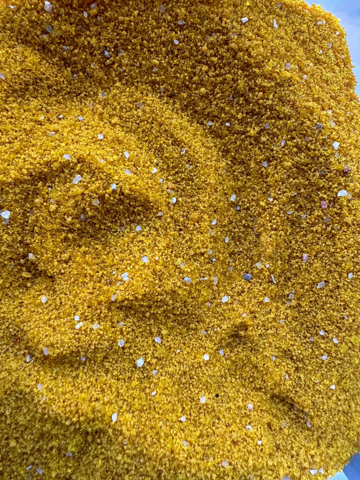 Close-up texture of golden Grains de jalba powder with small white granules scattered throughout the 30g traditional herb mixture