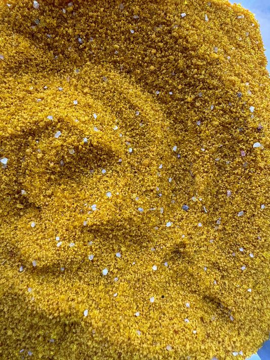 Close-up texture of golden Grains de jalba powder with small white granules scattered throughout the 30g traditional herb mixture