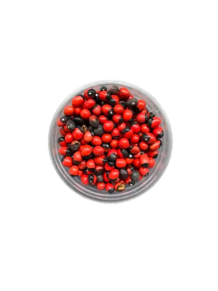 Habbat el Ashq seeds, red and black ritual beads in clear glass bowl on white background