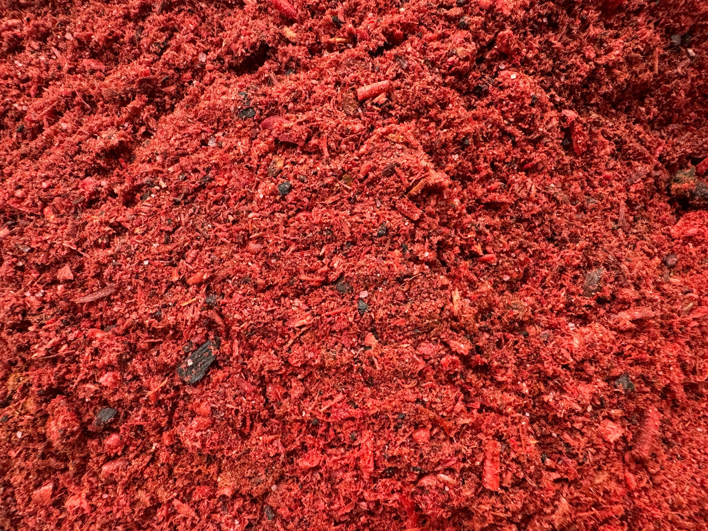 Egyptian amber incense powder in vibrant red color, close-up texture view of traditional oriental aromatic mixture