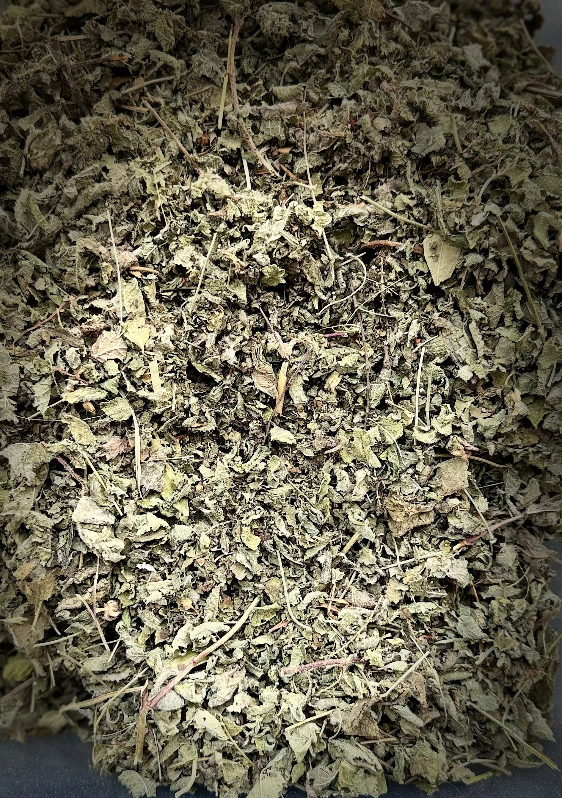 Dried Tamija Melissa lemongrass herbs showing finely crushed green-gray leaves and stems in traditional Moroccan blend