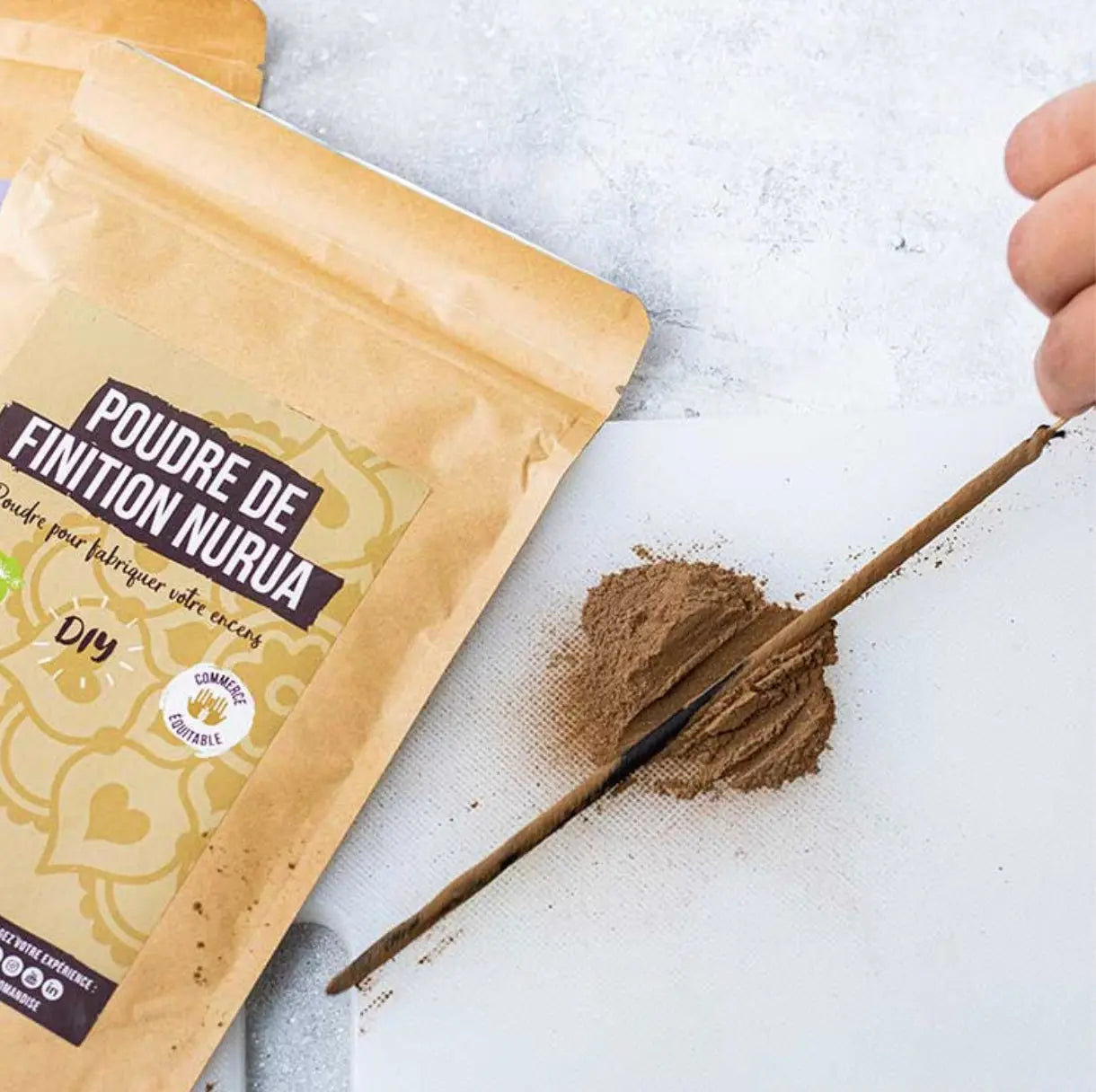 Nurua finishing powder for DIY incense making, brown powder next to golden package on white surface