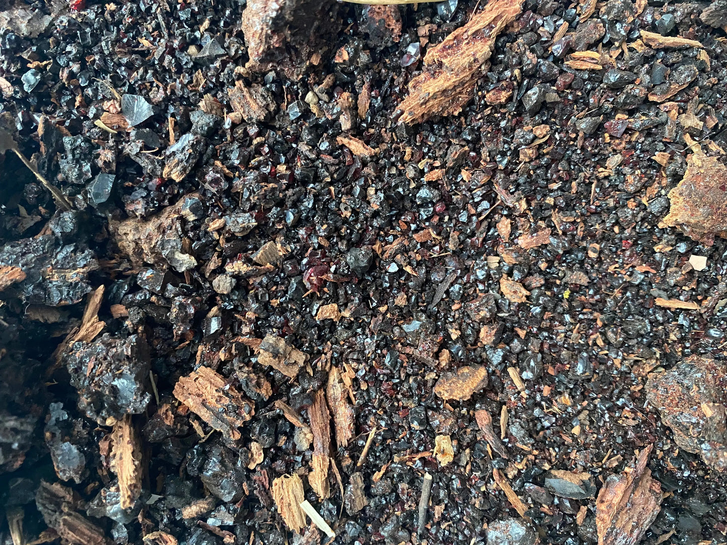 Close-up texture of Meqel azraq natural resin granules and fragments showing dark blue and brown organic material