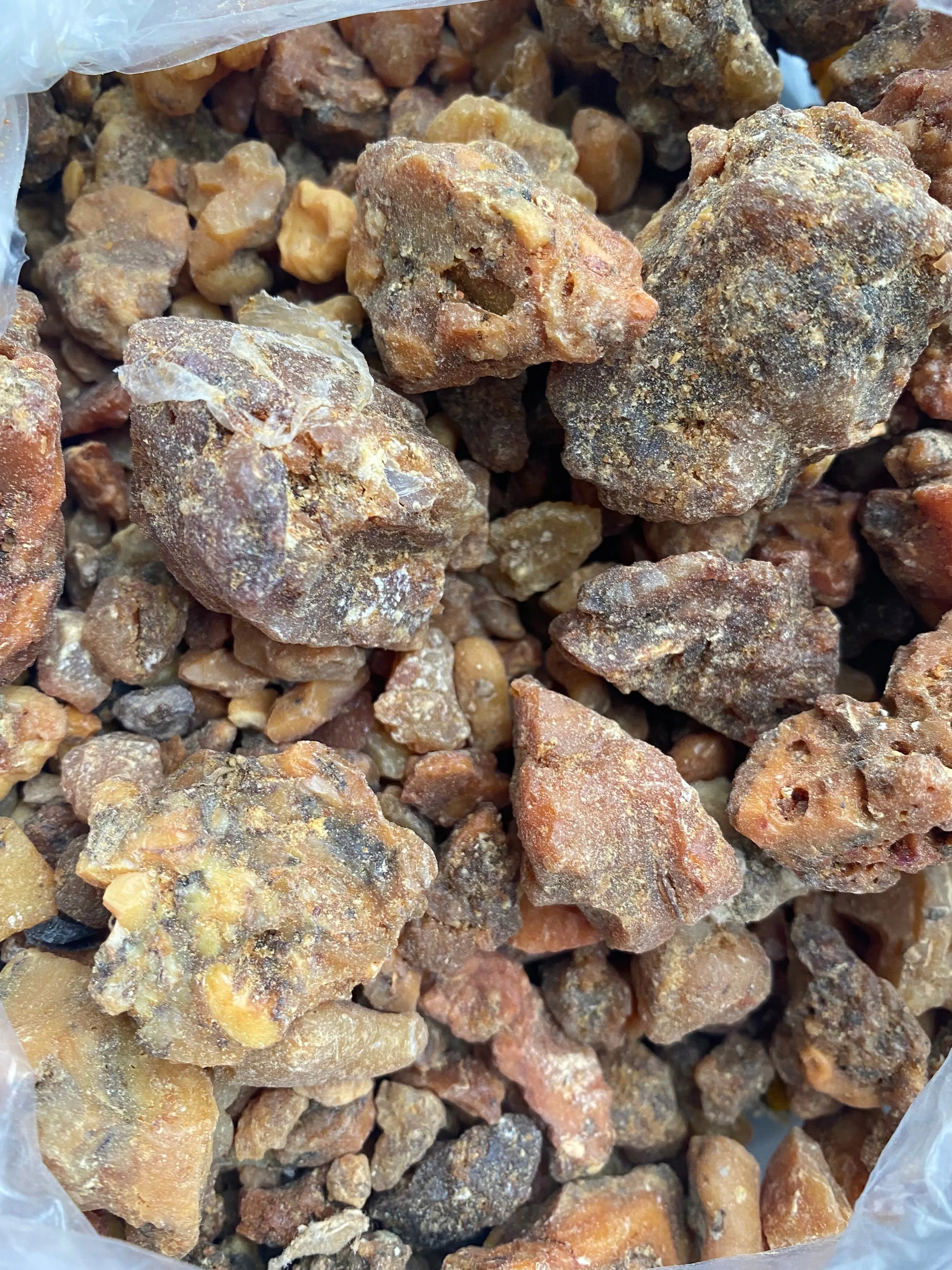 Raw haltite resin chunks in varying sizes and reddish-brown color, showing natural crystalline texture and formations