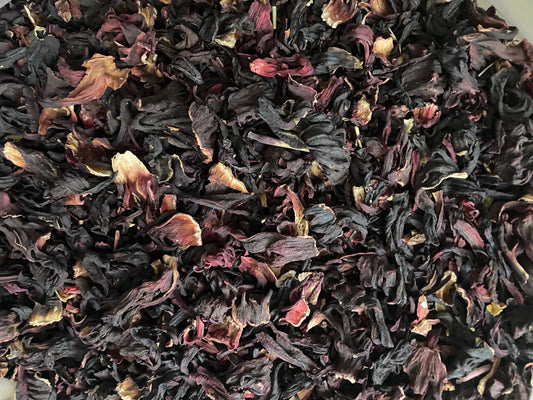 Dried Karkade hibiscus flowers in deep purple and burgundy colors, showing natural texture and loose leaf pattern