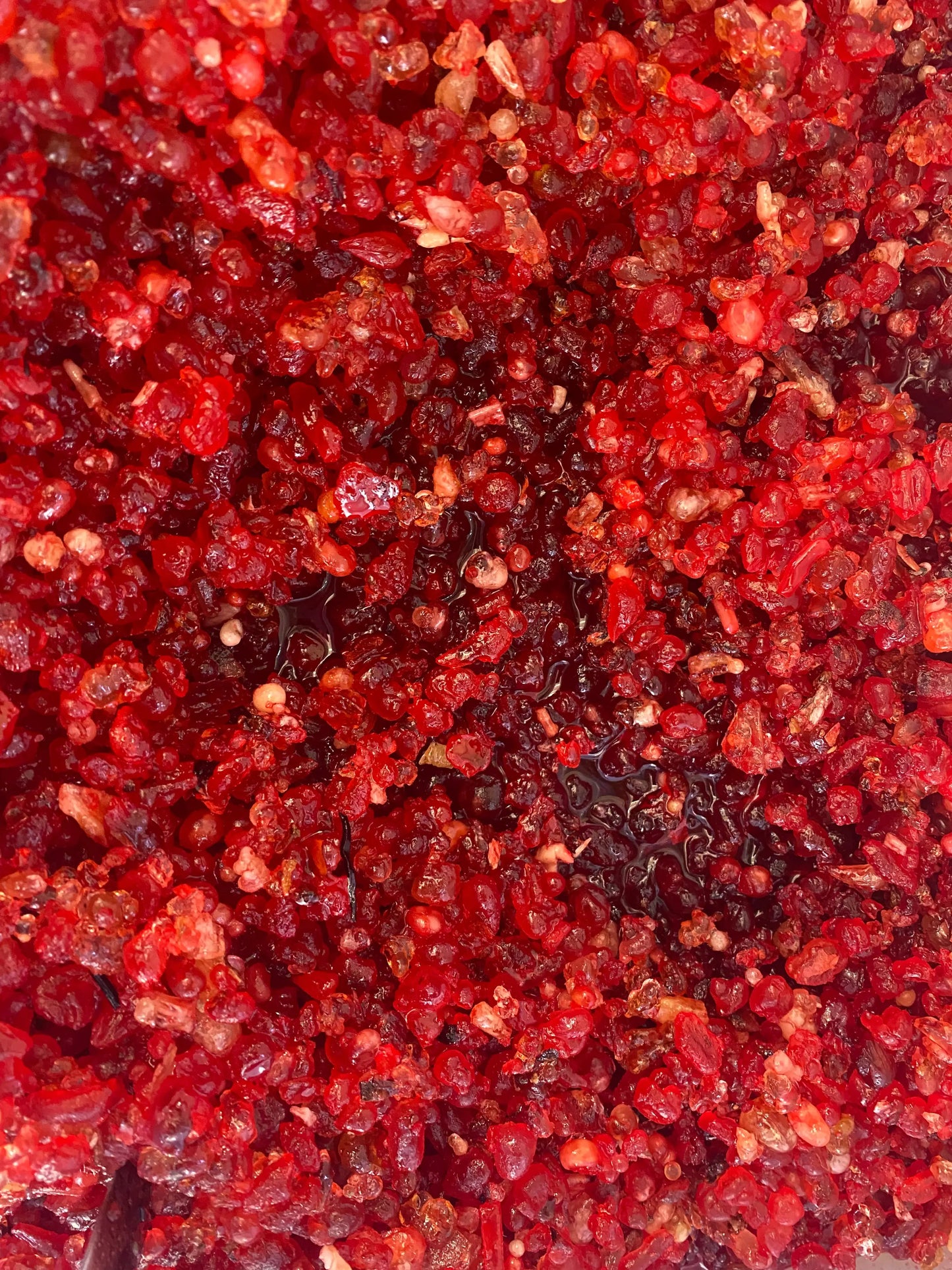 Closeup of red pomegranate incense granules from Oman showing rich texture and vibrant crimson color