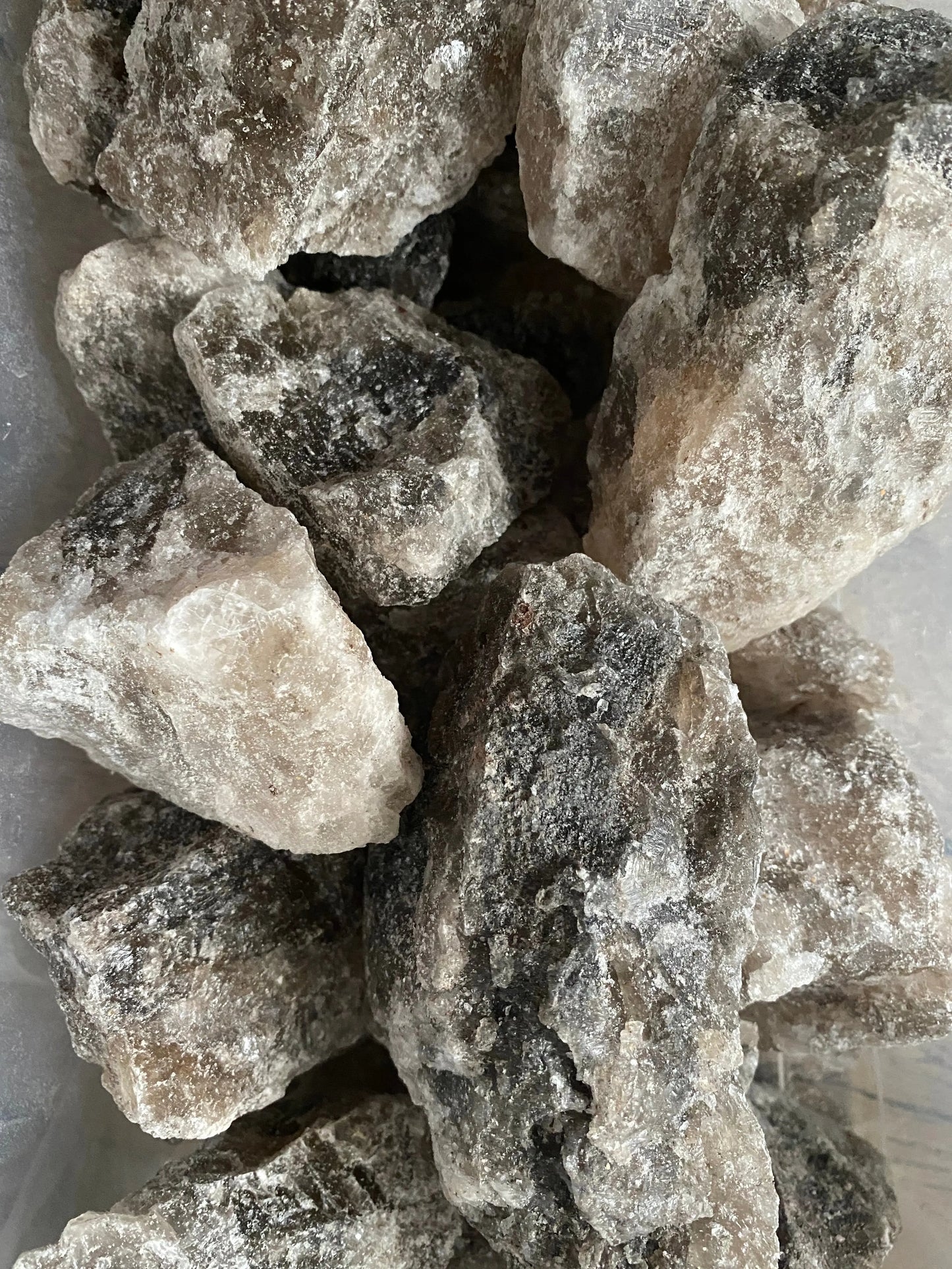 Raw chunks of Melha Haya rock salt crystals for spiritual protection and purification rituals, natural grey-white color