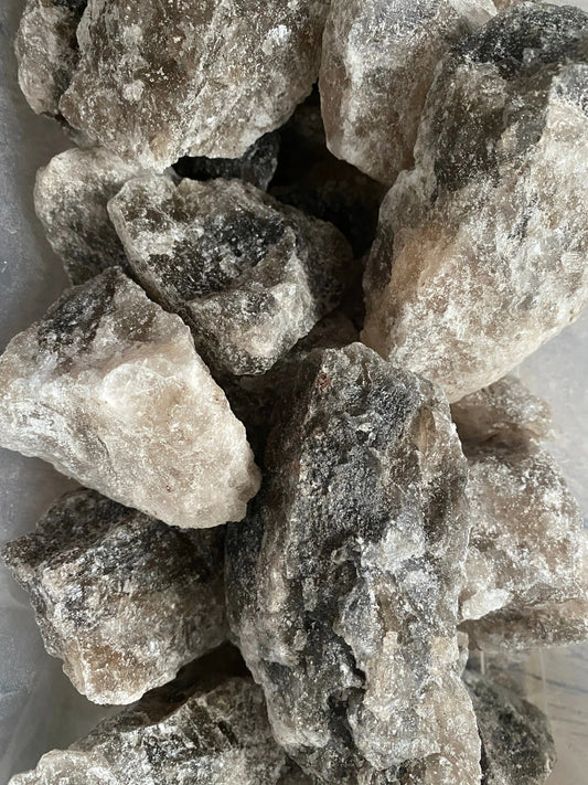 Raw chunks of Melha Haya rock salt crystals for spiritual protection and purification rituals, natural grey-white color