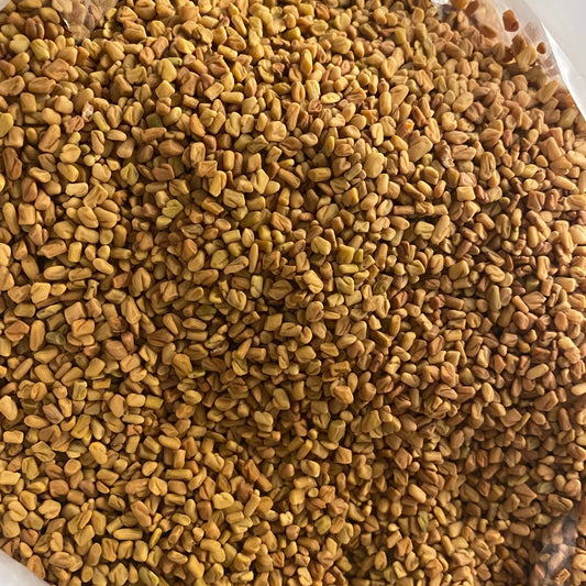 Close-up view of Fenugrec (Helba) seeds showing golden-brown dried whole seeds spread across the frame