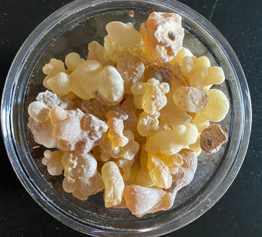 Premium Somali Luban incense resin in golden translucent chunks displayed in clear container, traditional frankincense tears