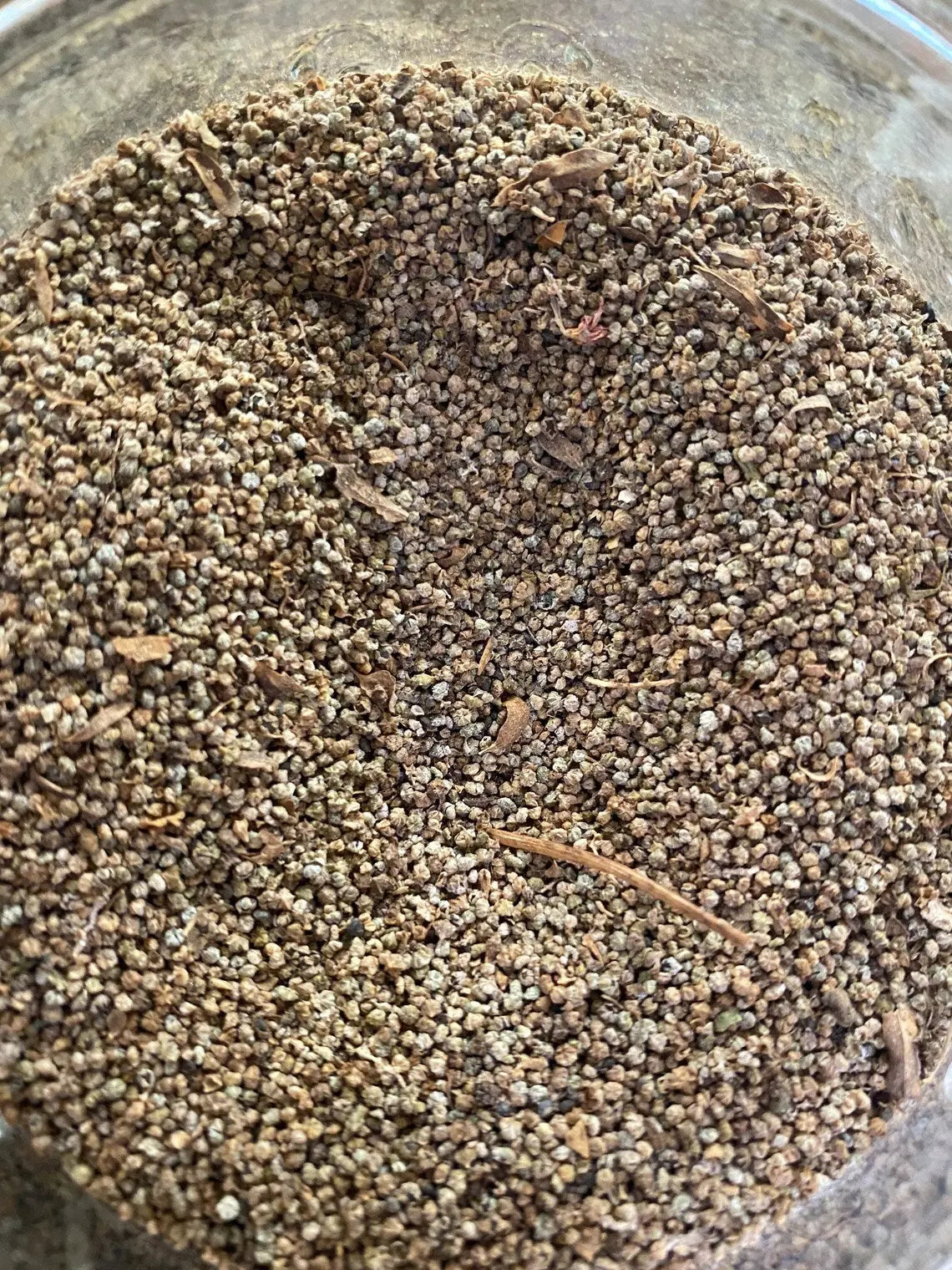 Ghelba 20g powder with fine brown and beige granules mixed with small twigs in glass container