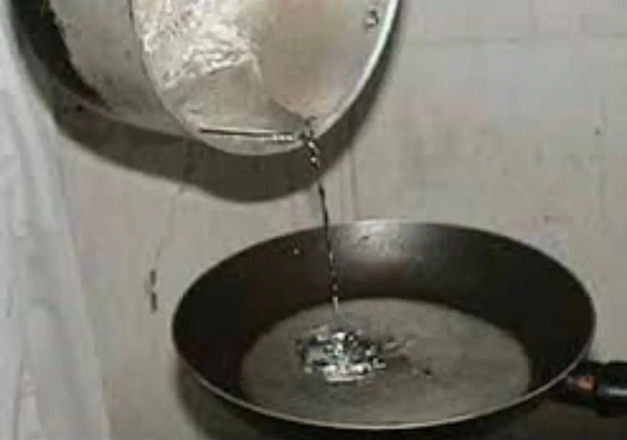 Rssass plomb ritual: Molten lead being poured from container into dark pan with water for traditional cleansing ceremony