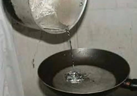 Rssass plomb ritual: Molten lead being poured from container into dark pan with water for traditional cleansing ceremony